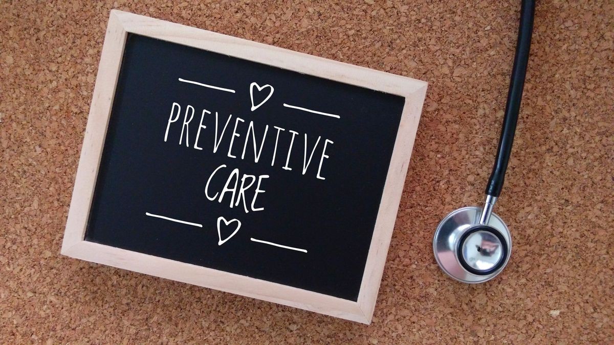 Stethoscope and Chalk board with inscription preventive care on a wooden table. Medical and health care concept.